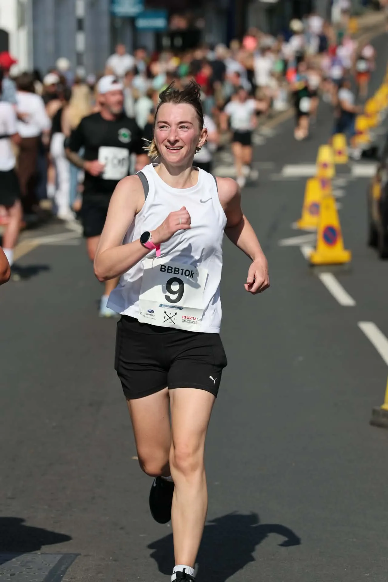 A runner smiling as she passes through the historic streets of Battle during the BBB10k